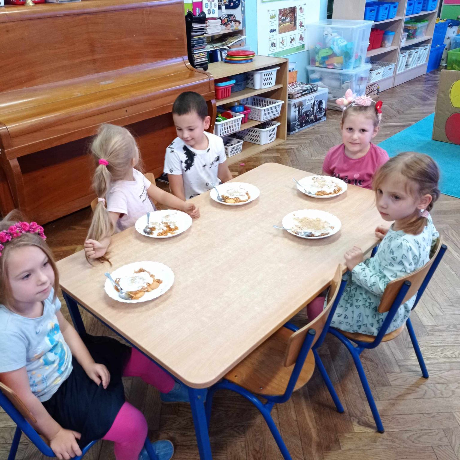 ciasto na talerzykach przed dziećmi siedzącymi przy stole